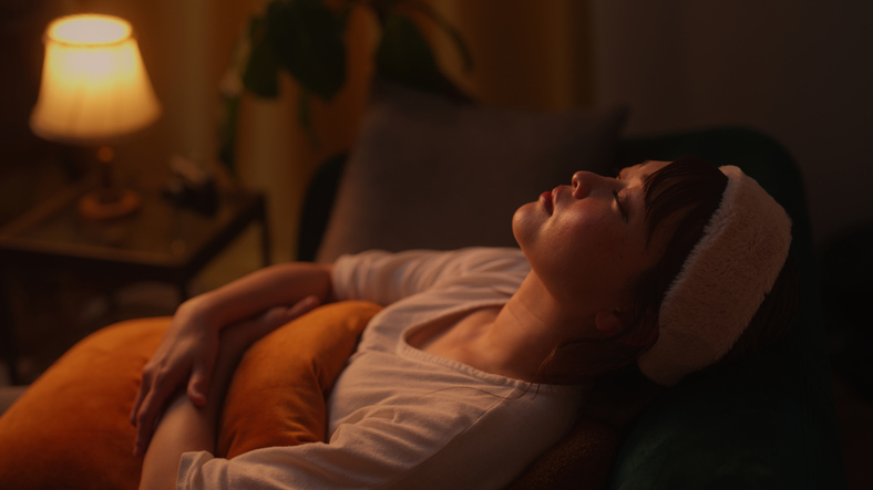 Woman lying peacefully in a dim room during acupuncture session, symbolizing calm, safety, and relaxation