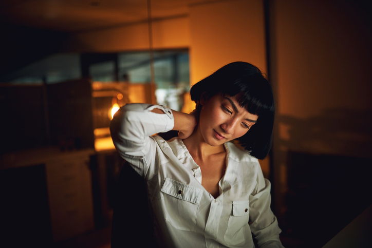 Woman rubbing her neck in discomfort, symbolizing tension, stress, and chronic pain relief through acupuncture