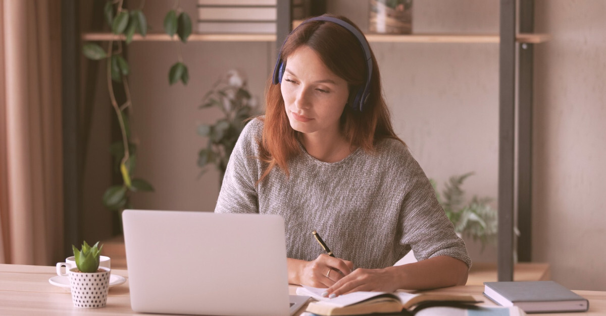 Woman studying acupuncture research at desk with laptop and medical books